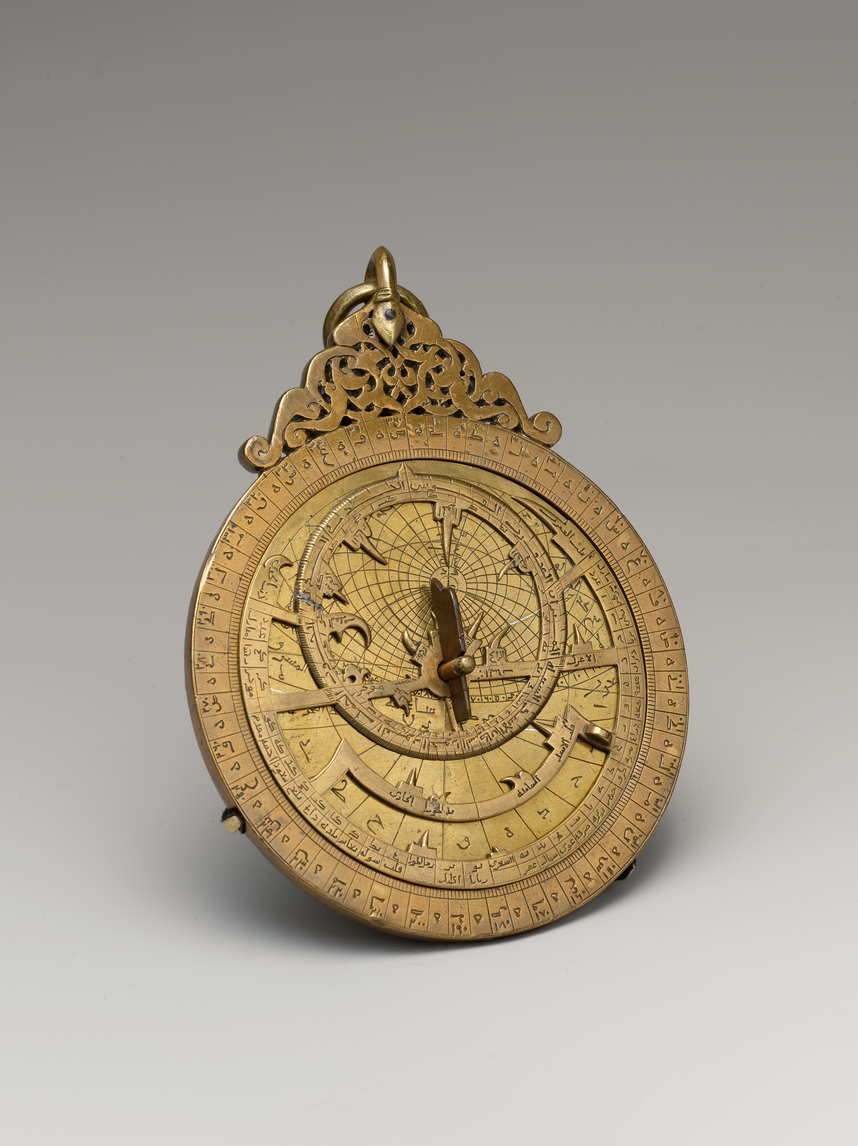 A thirteenth-century brass astrolabe with an intricate pierced star map.