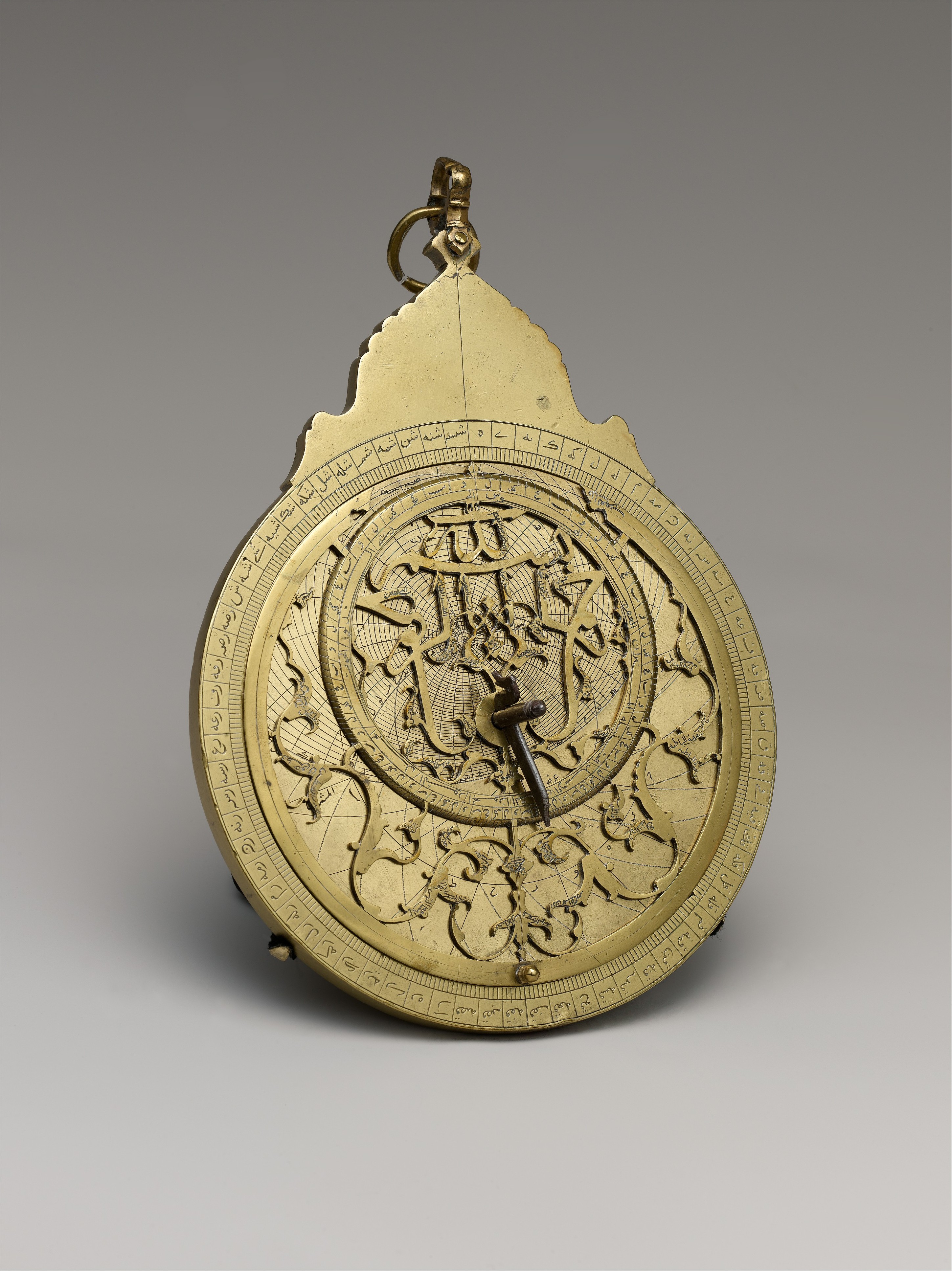 A circular brass planispheric astrolabe with engraved scales and a pierced rotating star map.